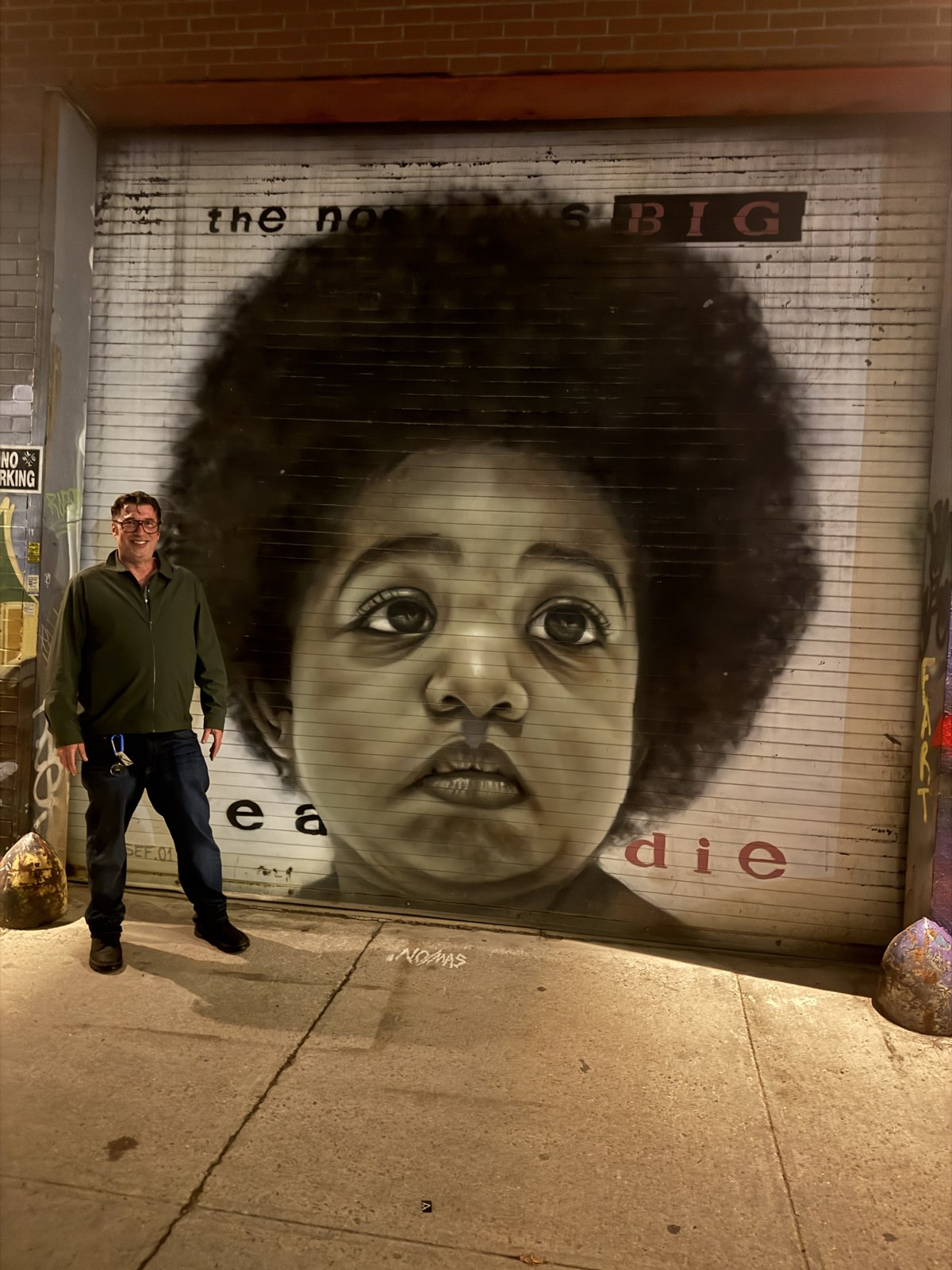Matthew in front of the Ready to Die mural, Brooklyn, at night